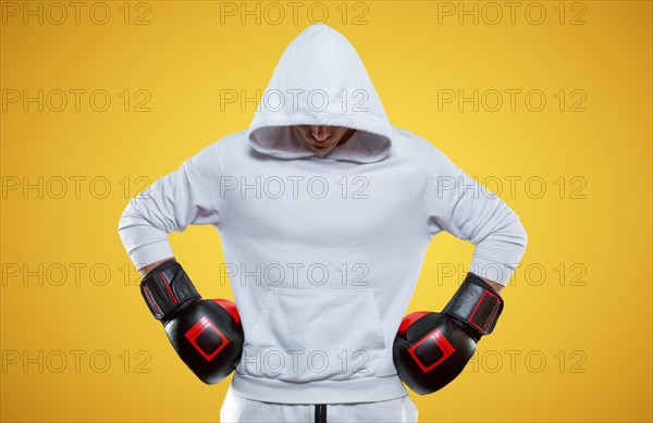 Male trainer posing in the studio with boxing gloves. White hoodie. Mixed martial arts concept. High image quality