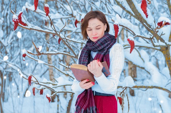 Oil portrait of a charming girl who is reading a book in the winter forest. Concept of Christmas