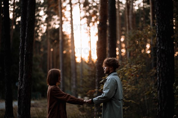 Beautiful fashionable couple in love in the forest at sunset in autumn