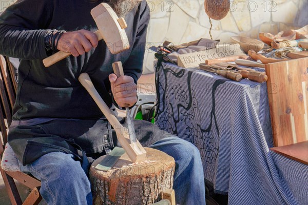 Craftsman working with wood at a street market at his stall of handmade wooden items