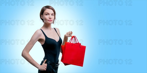 Beautiful young woman holding a craft red package in her hand. Shopaholics concept. Spenting. Gifts for the holidays. Black Friday. Shopping centers.