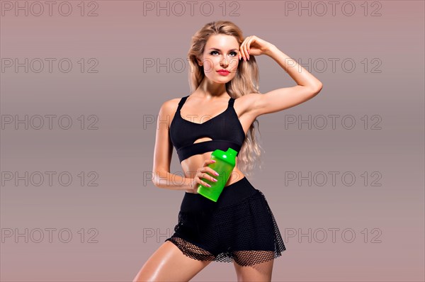 Charming girl with shaker in hands posing in studio.