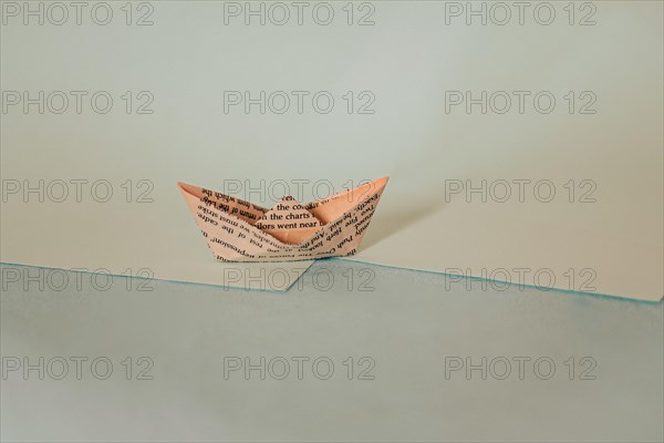 A simple origami paper boat on a diagonal split background with blue hues