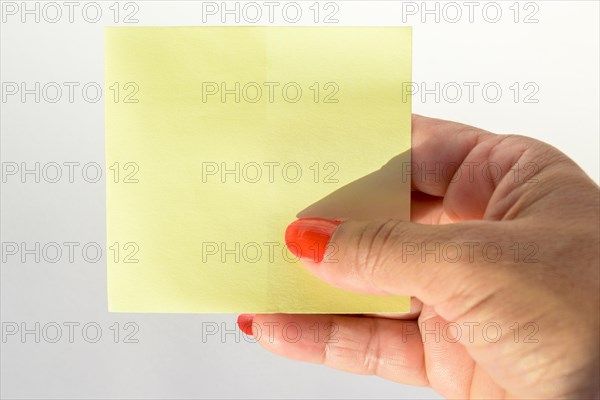 Woman's hand with painted nails holding blank letter paper on pure white background