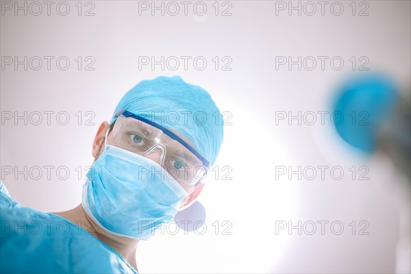 Male surgeon doctor in the operating room looking at the patient at the camera