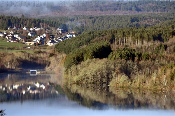 The Steinbach Dam near the national park community of Langweiler on the edge of the Hunsrueck-Hochwald National Park with fog on an early winter morning