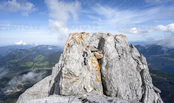 Female mountaineer climbing a via ferrata secured with a steel cable