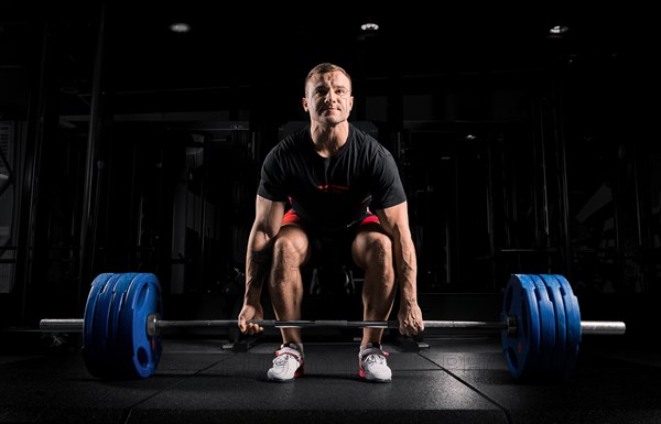 Professional athlete bent over the barbell and is preparing to lift a very heavy weight. Front view