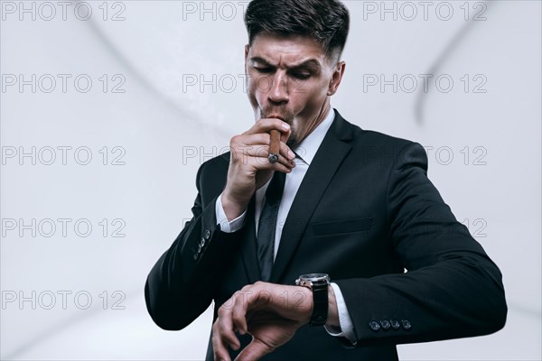 Portrait of a stylish man in a suit with a cigar. Business concept.