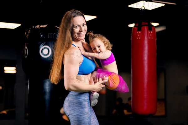 Mom and daughter in their hands posing in the gym.