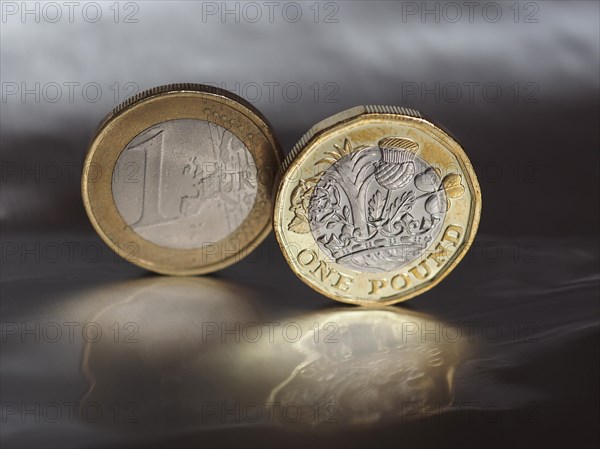 1 pound and 1 euro coin over metal background