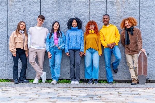 Portrait of a multi-ethnic group of friends standing leaning on an urban wall