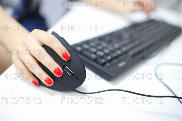 Girl's hand uses a vertical ergonomic joystick of a computer mouse. working at the computer