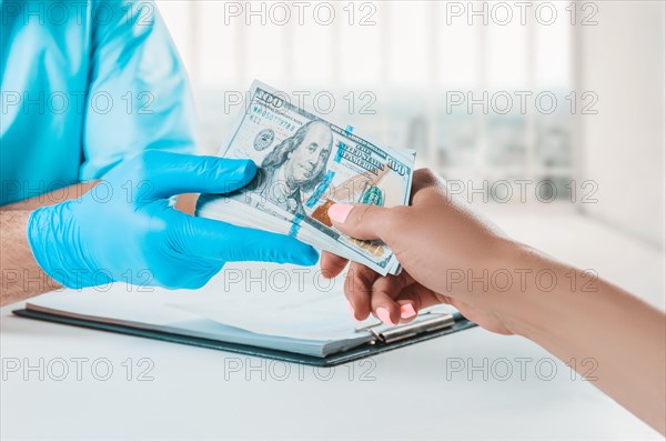 The doctor in the office takes a bribe from the patient. The concept of corruption in medicine.