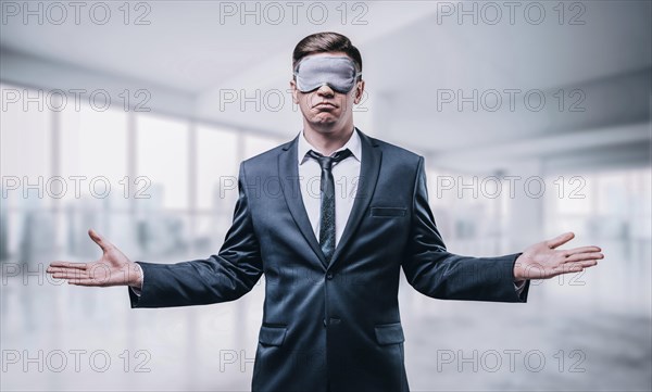 Portrait of a man in a mask for sleeping. He stands in an unfinished skyscraper. Blind business concept. Building.