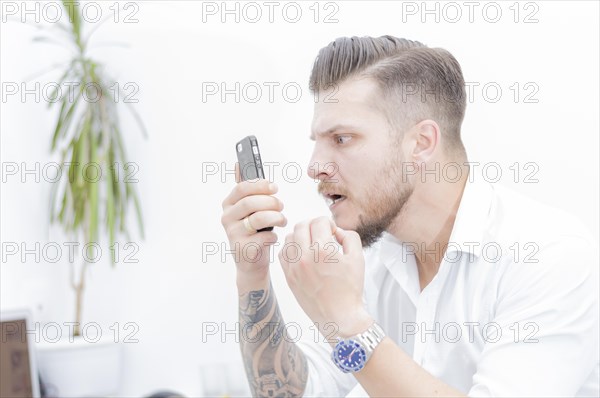 Man in a shirt looks at the smartphone screen in surprise. Concept of unsuccessful betting on games