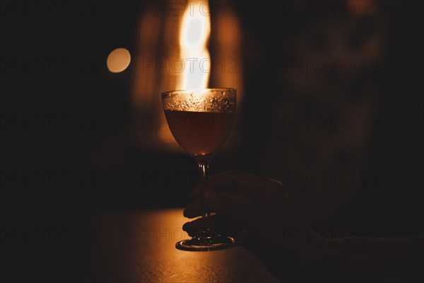 Image of a glass with a cocktail in a night bar against the background of a fiery heater. Restaurant concept