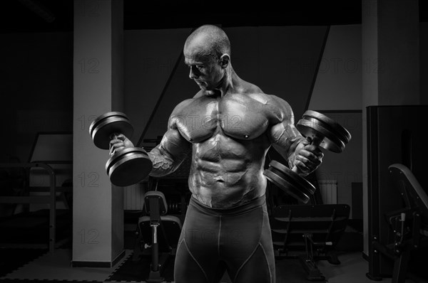 Professional weightlifter is training in the gym. Dumbbell Curl. Bodybuilding concept.