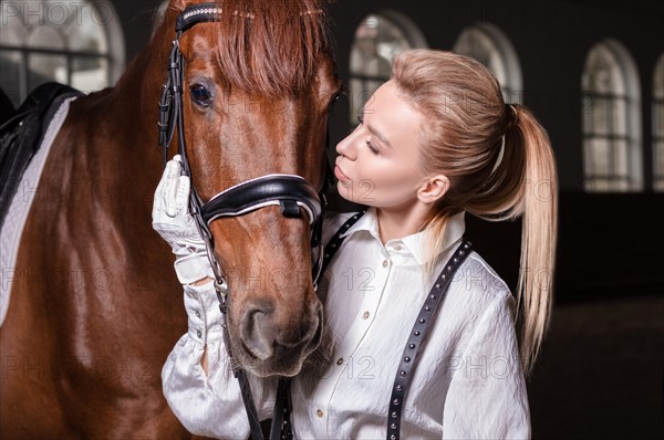 Portrait of a stylish woman hugging a thoroughbred horse. Love and care concept.