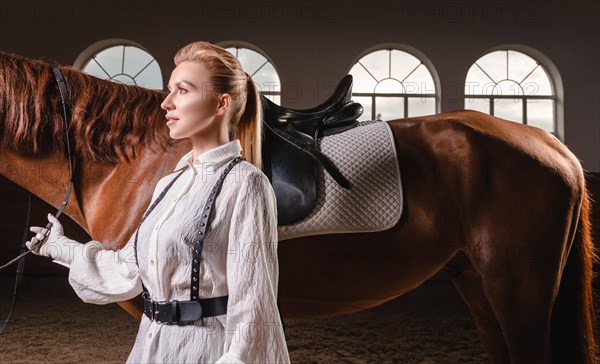 Portrait of a stylish woman hugging a thoroughbred horse. Love and care concept.