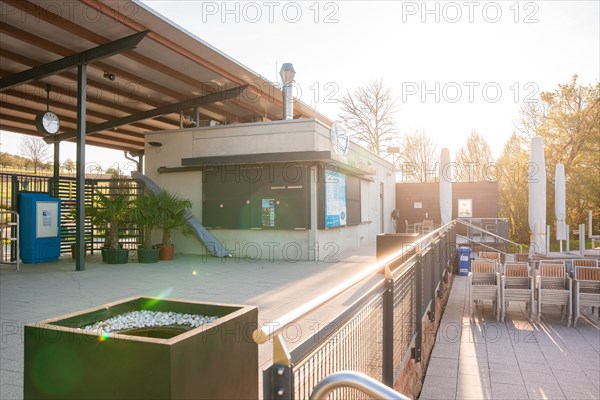 Empty seating area in the outdoor pool with plants and sun protection over chairs