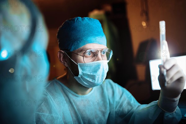 Scientist doctor in a dark laboratory with a test tube of a medicinal product