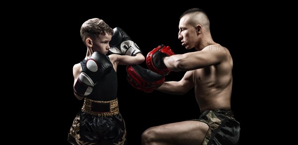 Thai boxing coach practicing punches with his student. Kickboxing concept