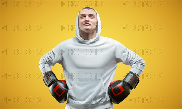 Male trainer posing in the studio with boxing gloves. White hoodie. Mixed martial arts concept. High image quality