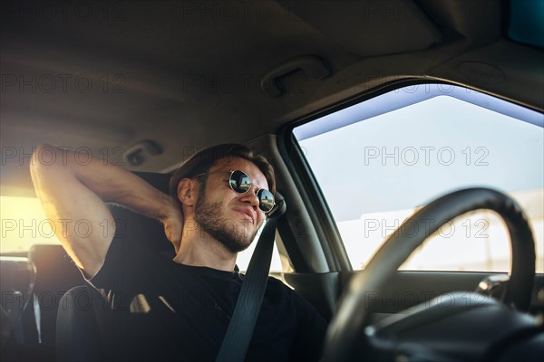 Young handsome male driver tired of sitting behind the wheel