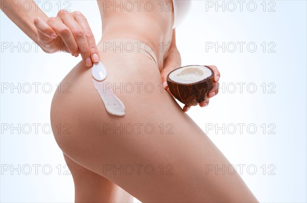 Image of female hands applying natural coconut cream to the buttocks. Medical concept. Anti-cellulite ointments.