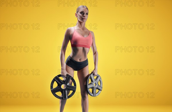 Delightful athlete posing in the studio with weights in her hands. The concept of sports