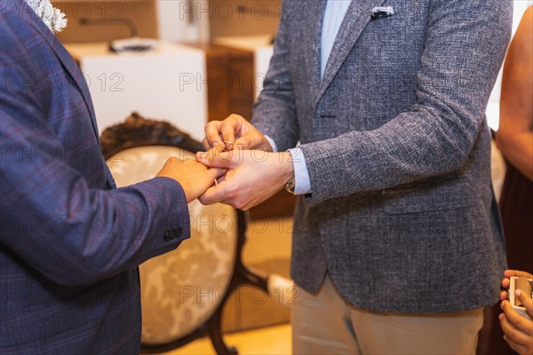 Gay wedding groom placing ring on husband at ceremony