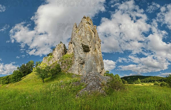 Striking limestone rock formation Burgstein with blue and white sky in the upper Altmuehltal surrounded by green vegetation