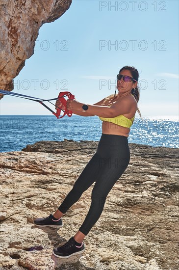 FITNESS LATIN WOMAN IN SPORTS SET TRAINING WITH ELASTIC BAND