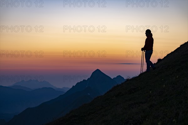 Mountaineer on mountain ridge with Rothorn peak in the background at blue hour