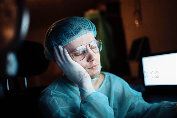 A tired young surgeon falls asleep in the resident's room after hours of complex surgery