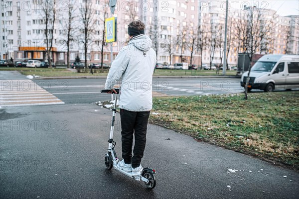 Young stylish guy rides an electric scooter around the city