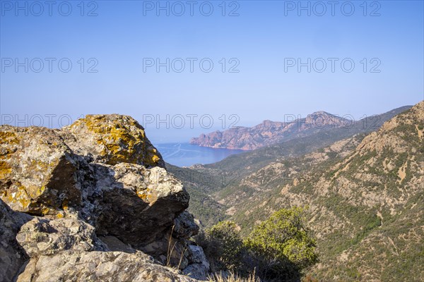 View from Col de Palmarella of the sunny coastal landscape with mountains in the background