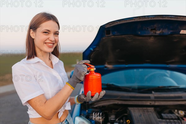 Young beautiful and hot woman driver holds a fire extinguisher in her hands