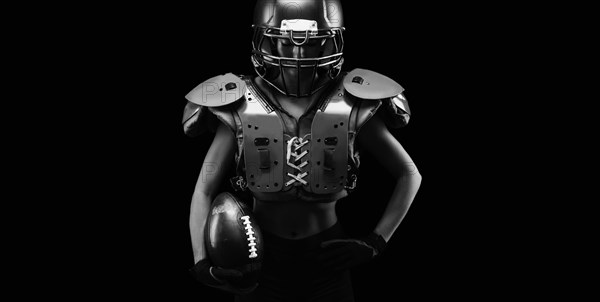 Portrait of a girl in the uniform of an American football team player. Black background. Sports concept.