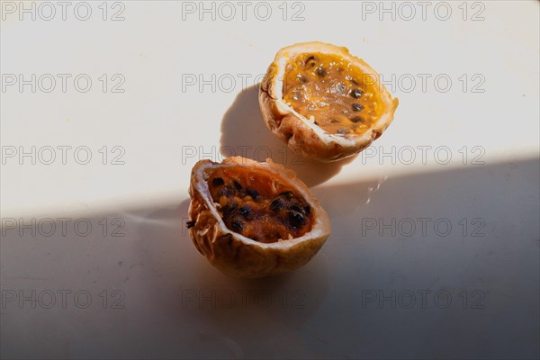Juicy cut halves of a passion fruit with visible seeds in the sunlight