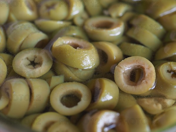 Sliced green olives in brine background