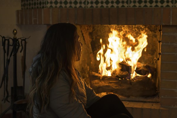 Latin woman sitting in front of the fireplace in the cold winters