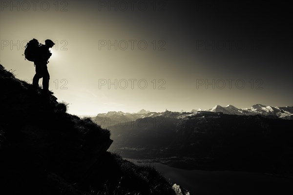 Mountain ridge with mountaineers and Swiss mountains and Lake Thun in the background at sunrise