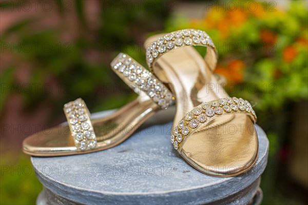 Gold-colored high heels with shiny rhinestones on a display stand
