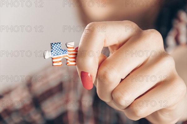 Portrait of a girl holding a puzzle with the USA flag. Concept of emigration