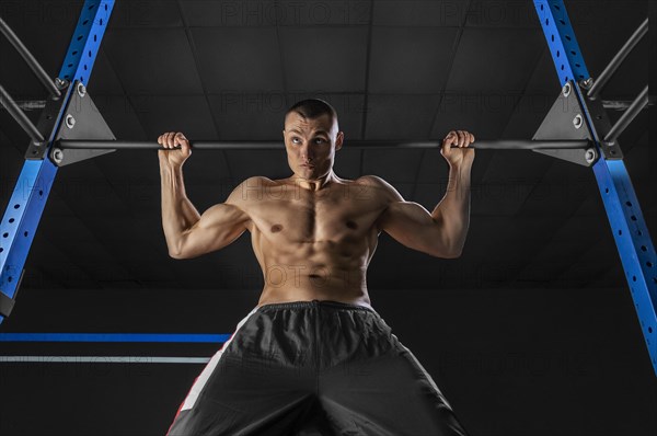 The athlete pulls himself on the horizontal bar behind his head. The concept of sport and healthy lifestyle.