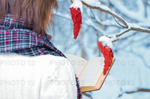 The girl reads a book in the winter forest. Learning concept. Winter's tale.