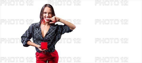 Sexy tall brunette holding a red jewelry box. She bites her finger erotically. The concept of gifts and congratulations.