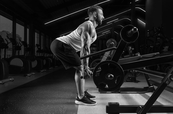 Handsome young man pumps his back in a special machine. Deadlifting. Fitness and bodybuilding concept.